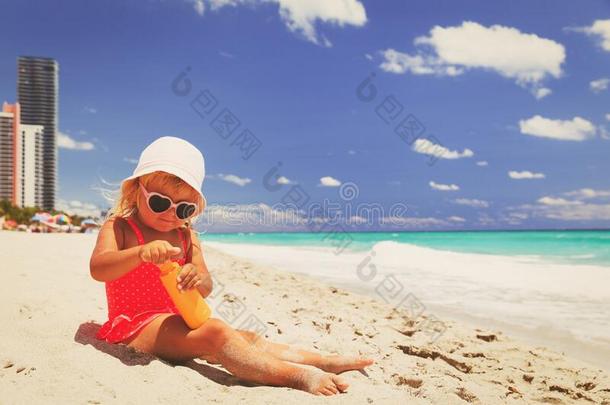 太阳保护-小的女孩和防晒霜乳霜向海滩