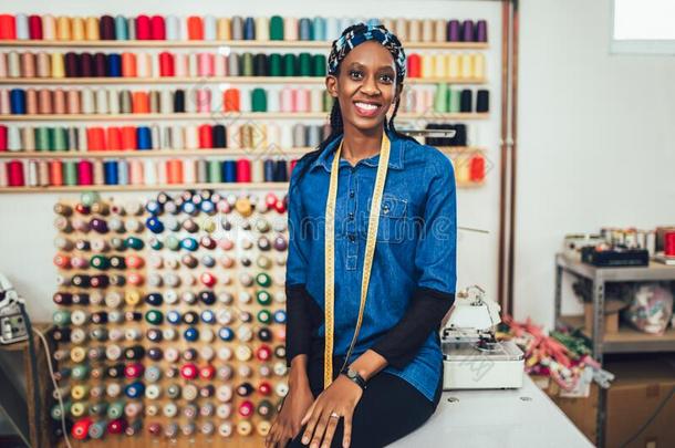 幸福的非洲的裁缝女人采用工作室.背景关于富有色彩的