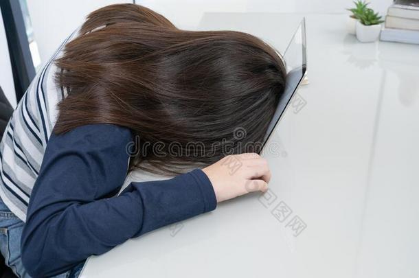 年幼的女人长的头发落下睡着的向书桌和便携式电脑