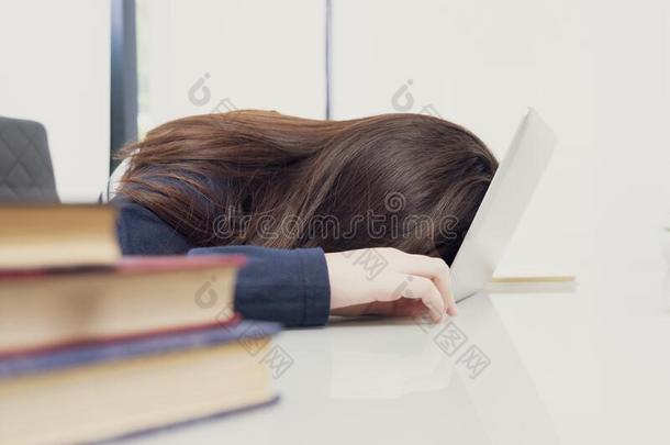 年幼的女人长的头发落下<strong>睡</strong>着的向书桌和便携式电脑