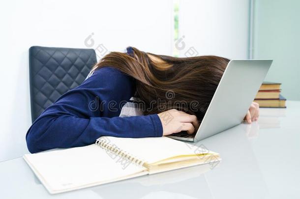 年幼的女人长的头发落下睡着的向书桌和便携式电脑