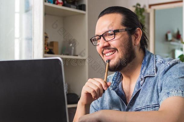 微笑的年幼的男人电讯家庭办公/在家办公采用前面关于指已提到的人便携式电脑