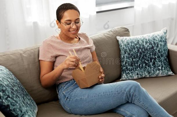 非洲的女人吃食物和筷子在家