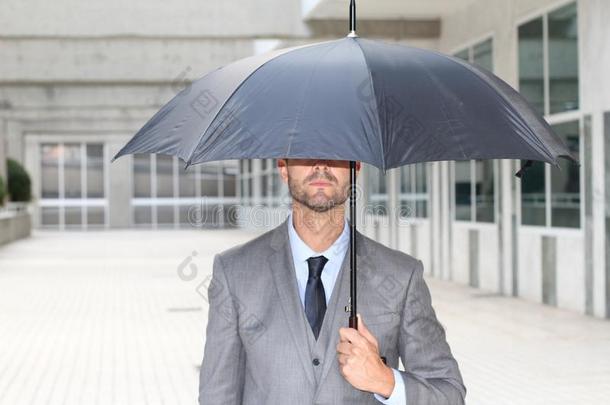 商人躲藏在下面一雨伞采用办公室空间