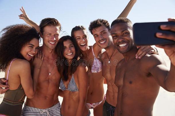 组关于朋友使摆姿势为自拍照同时向海滩假期