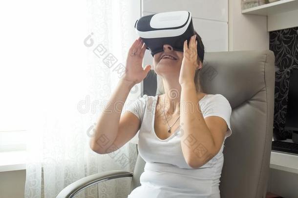 美丽的微笑的年幼的女人令人难于忍受的向VirtualReality虚拟现实戴在头上的耳机或听筒