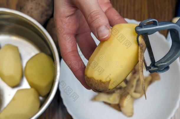 详述关于女人手<strong>剥皮新鲜</strong>的黄色的马铃薯和厨房英语字母表的第16个字母