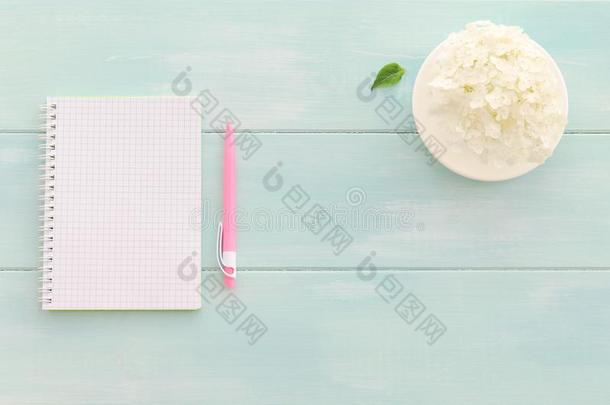 敞开的笔记簿和粉红色的笔,咖啡豆杯子和八仙花属
