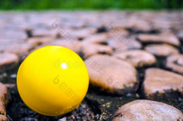 黄色的塑料制品球向棕色的St向es质地和背景.岩石