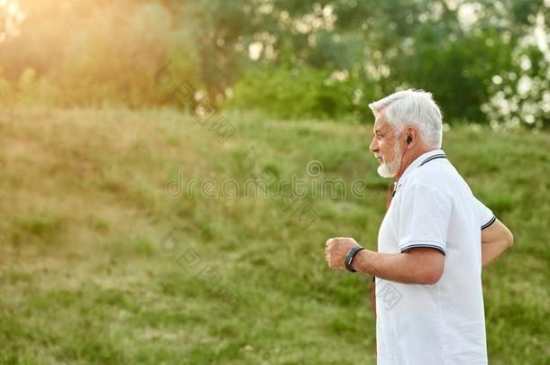 老的男人跑步采用城市公园向日落.