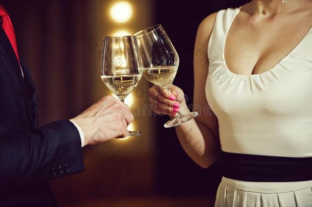 对发出叮当声眼镜和白色的葡萄酒在会议或婚礼