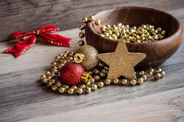 木制的碗和圣诞节金色的珍珠链子,红色的和金glittering闪烁
