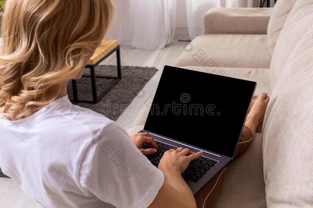 女人向沙发工作的向便携式电脑和假雷达空白的屏幕.空的