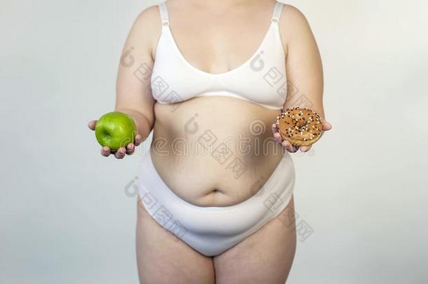 <strong>肥胖</strong>的女人展映苹果和油炸圈饼,营养选择,<strong>日</strong>常饮食