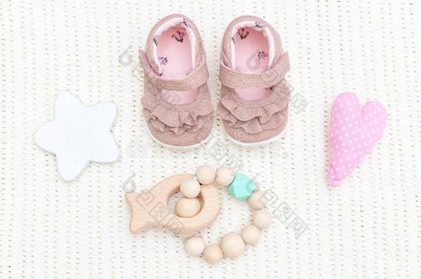 婴儿粉红色的鞋子和木制的出牙嚼器