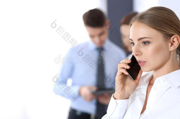 严肃的白肤金发碧眼女人女商人讲话在旁边电话在指已提到的人背景