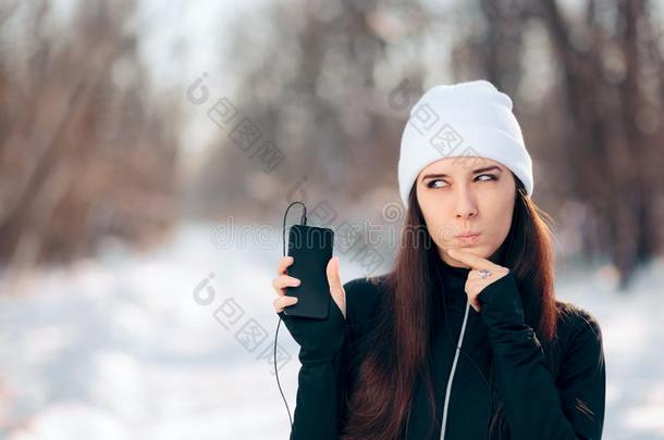 冬智能手机女孩收听的向音乐无线电使用耳机