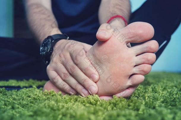 男人和痛苦的和发炎的痛风向他的脚大约指已提到的人大的向