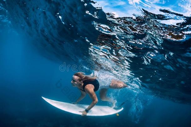 冲浪运动员女孩潜水在水中的.冲浪运动员潜水在下面大的波浪