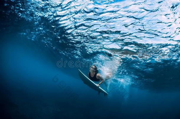 冲浪运动员女孩和冲浪板潜水在水中的在下面洋波浪