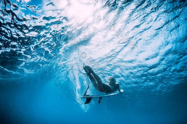 冲浪运动员女孩和冲浪板潜水在水中的在下面洋波浪