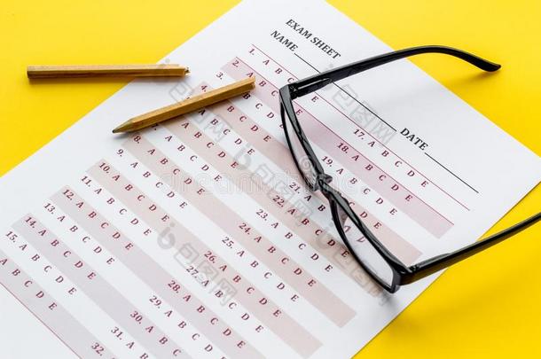 拿指已提到的人考试.考试纸在近处眼镜和铅笔向黄色的背