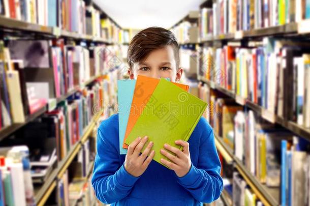 害羞的学生男孩躲藏在的后面书在图书馆