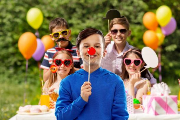 幸福的男孩和红色的丑角鼻子在生日社交聚会