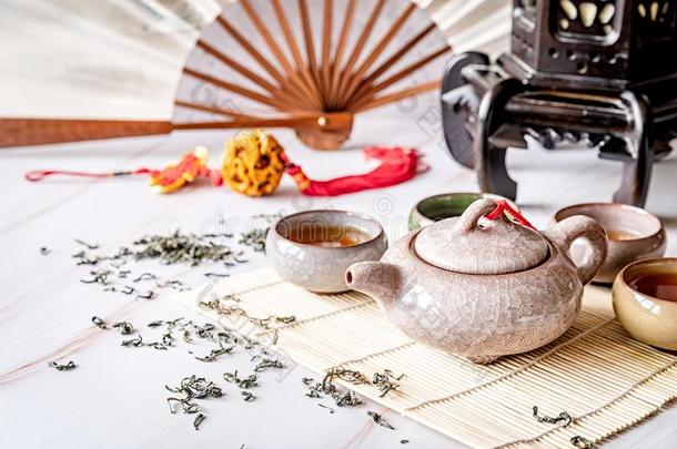 亚洲人茶壶和茶杯向竹子桌子装饰和颏