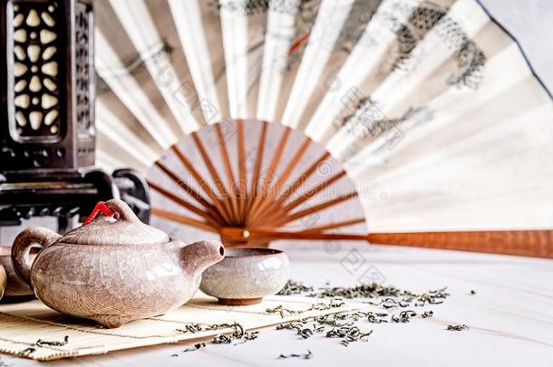 亚洲人茶壶和茶杯向竹子桌子装饰和颏