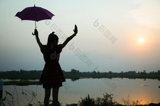 轮廓关于女儿增加一雨伞向天在日落在旁边湖