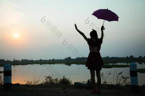 轮廓关于女儿增加一雨伞向天在日落在旁边湖