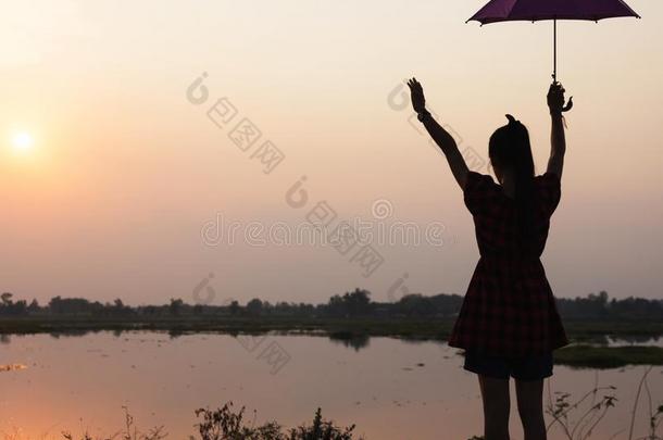 轮廓关于女儿增加一雨伞向天在日落在旁边湖