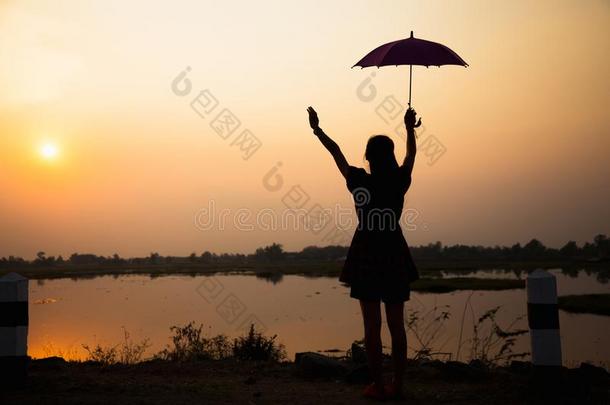 轮廓关于女儿增加一雨伞向天在日落在旁边湖