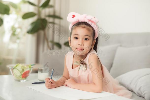 小的女孩绘画照片在表和绘画工具在室内