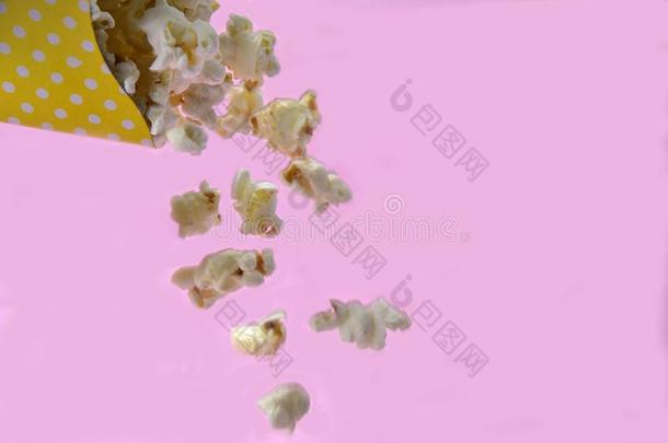 爆米花落下从纸包装和粉红色的背景