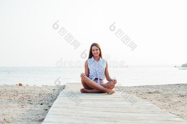 鞣酸处理的<strong>女人</strong>和长的头发做瑜伽向海滩在旁边指已提到的人海