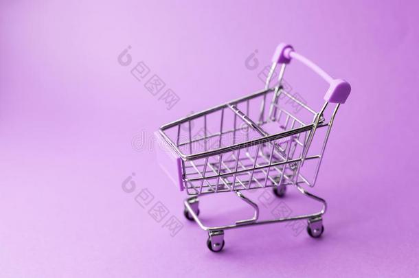 空的金属购物手推车向紫色的背景.打折扣和