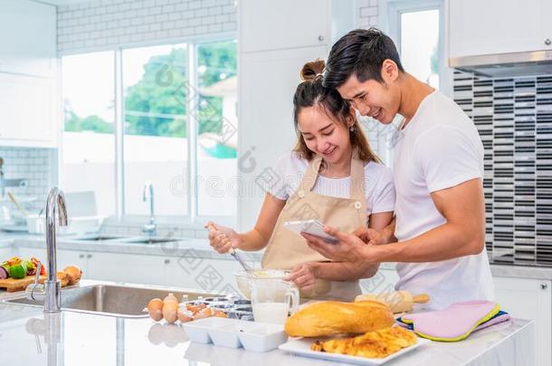 幸福的亚洲人一对烹饪术和烘焙蛋糕同时采用厨房