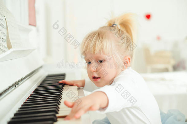 漂亮的小孩女孩演奏钢琴采用一工作室.