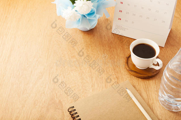 笔记簿和铅笔,咖啡豆杯子,日历,瓶子水和花
