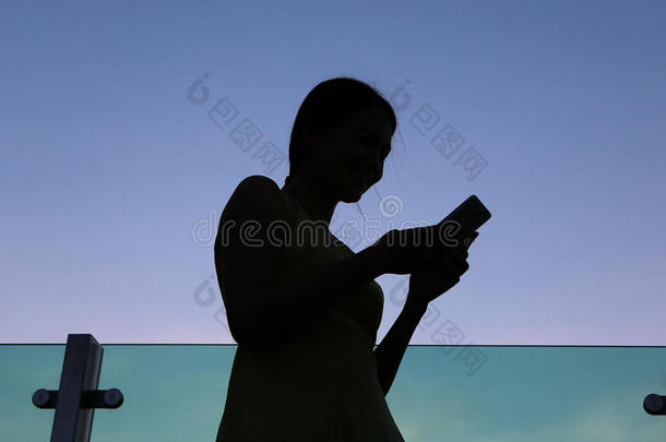 轮廓关于女人使用智能手机在日落