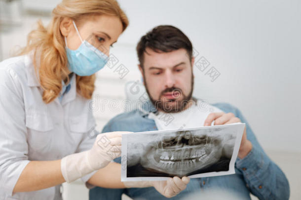 严肃的有才能的牙科医生讲解指已提到的人诊断