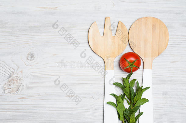 番茄和薄荷树叶和木制的餐具向白色的木制的后面