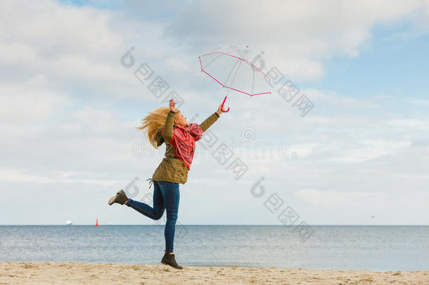 女人用于跳跃的和<strong>透明</strong>的<strong>雨伞</strong>向海滩