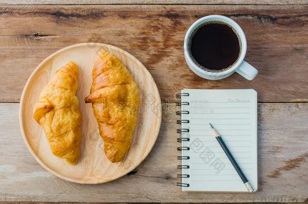 羊角面包咖啡豆笔记簿和铅笔向指已提到的人木制的表-t向e