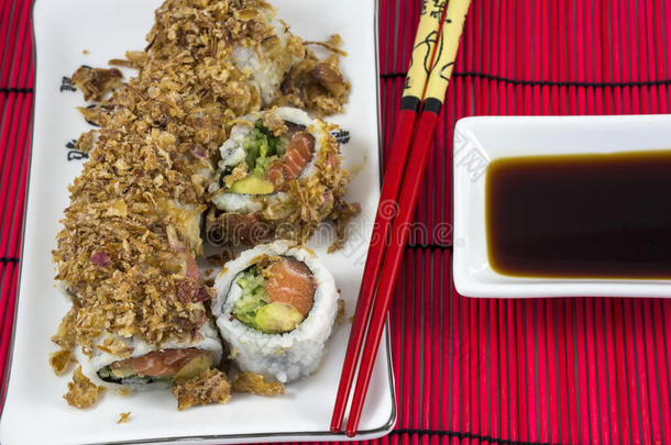 亚洲人寿司和鲑鱼和鳄梨向指已提到的人白色的盘子和红色的英语字母表的第2个字母