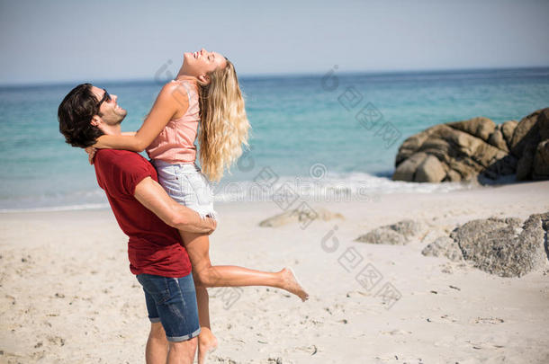 幸福的男朋友运送的女朋友在期间起立在海滩