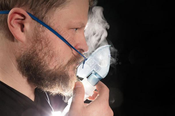 男人呼吸通过喷雾器面具
