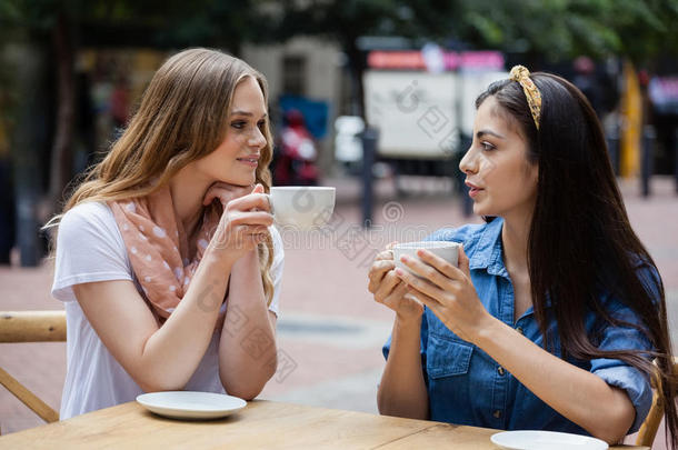 朋友喝饮料咖啡豆在期间一次在人行道咖啡馆